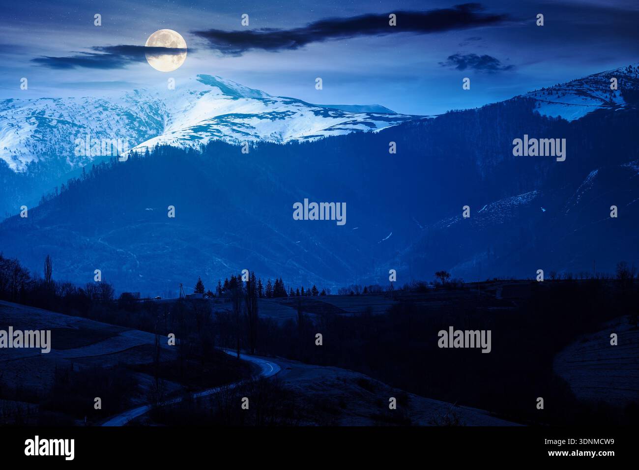 carpathian mountains of ukraine in early spring at night. view of countryside landscape with rolling hills and snow covered peak in full moon light. i Stock Photo