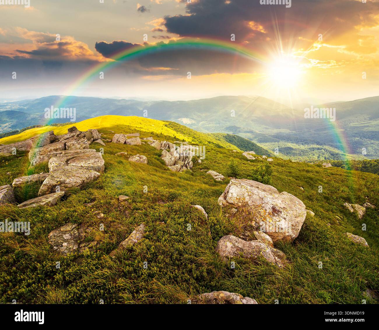 mountain landscape in summer with rocks at sunset. green grass under blue sky in dramatic evening light. alpine meadow and rolling hills with boulders Stock Photo
