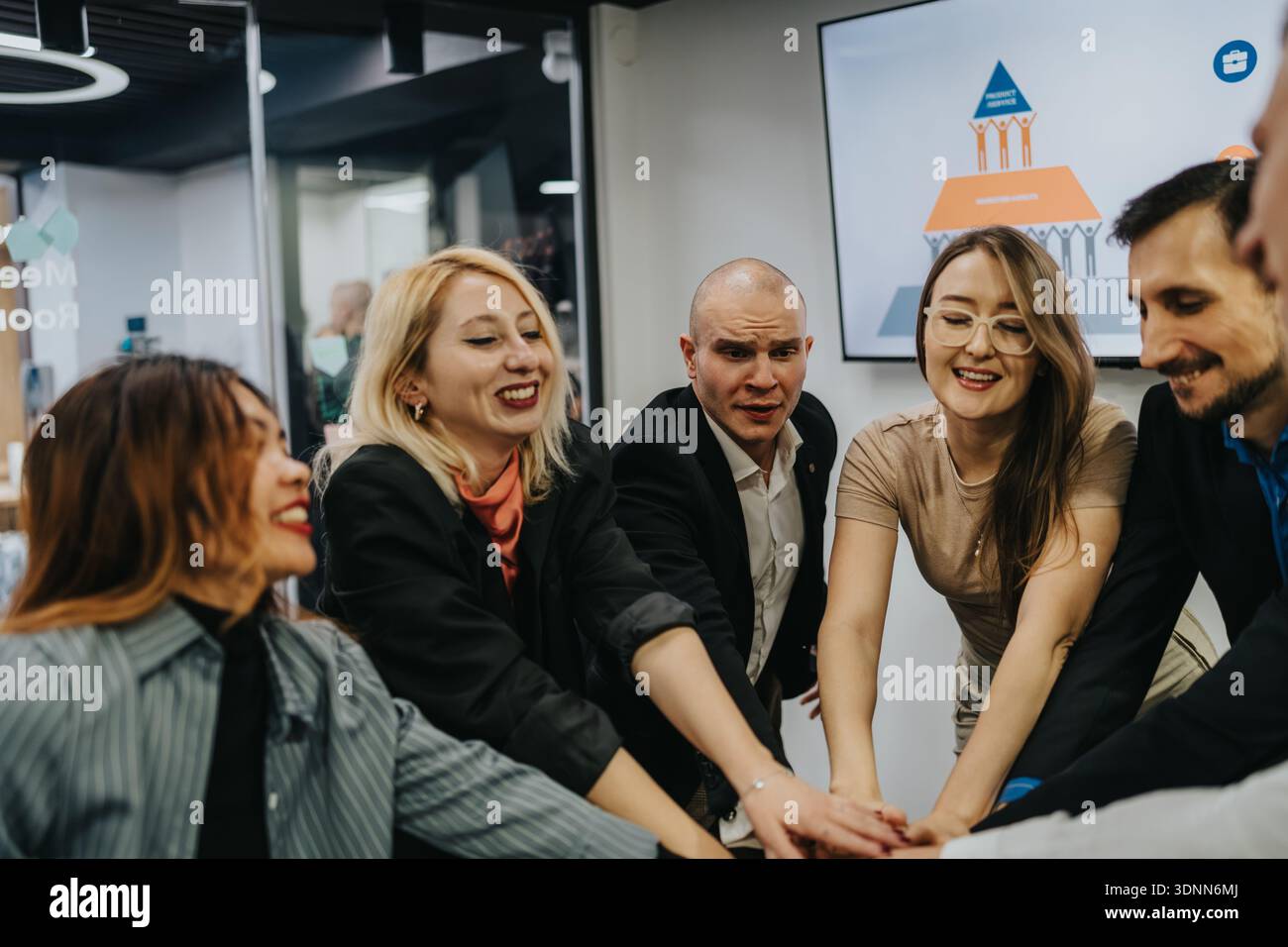 Diverse group of professionals join hands in a modern office team ...