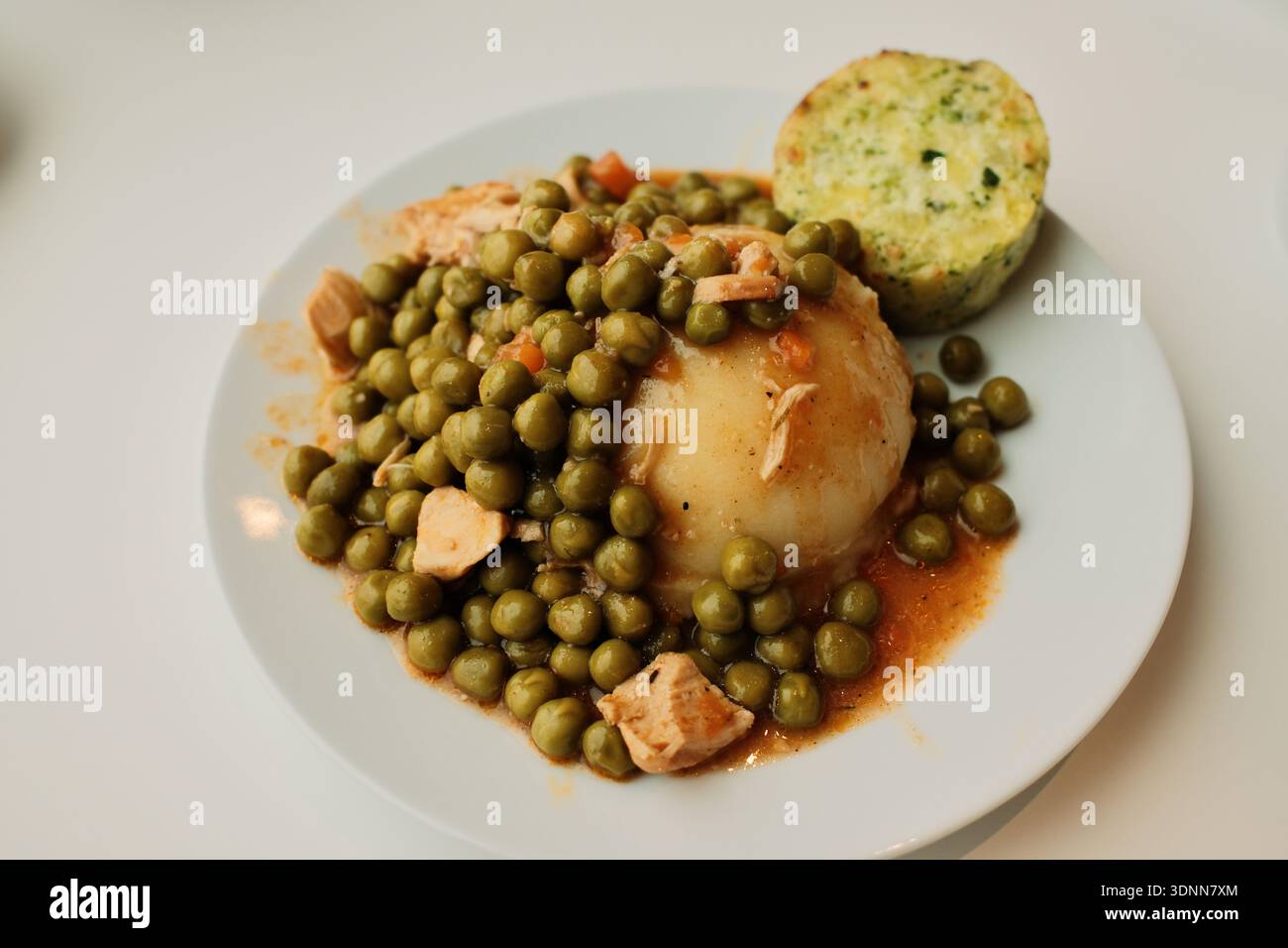 Mashed potatoes topped with green pea stew and chicken pieces on a white plate. Simple comfort food dish, homemade lunch concept with vegetables and Stock Photo