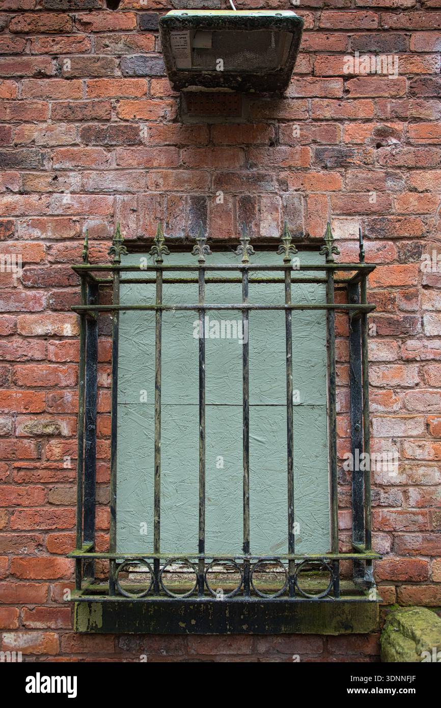 Boarded up Window and Iron Security Bars on Red Brick Building Stock Photo