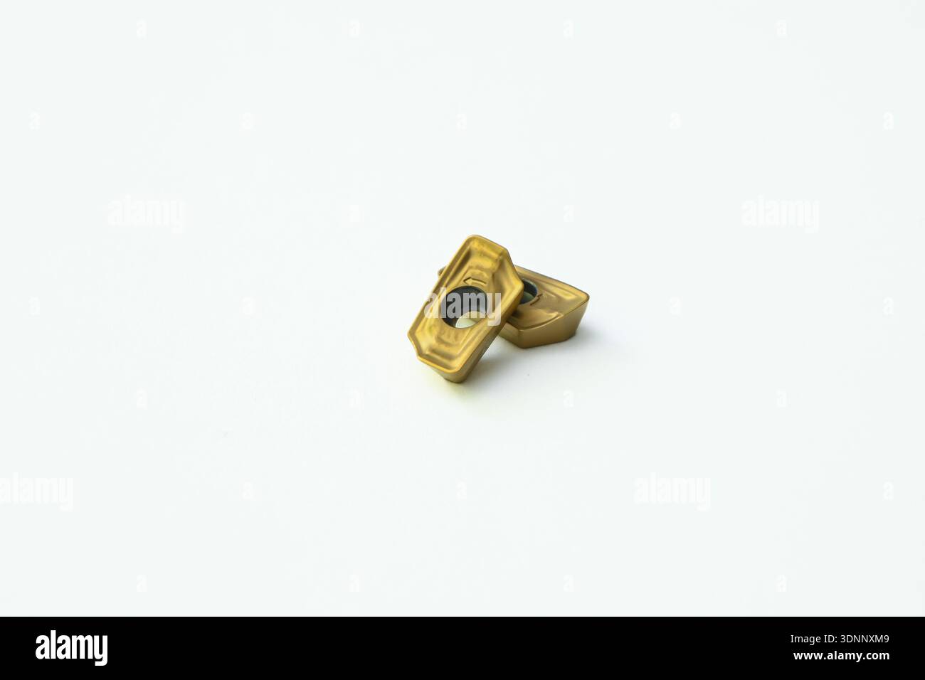 Two titanium nitride coated carbide inserts on a white background. Stock Photo