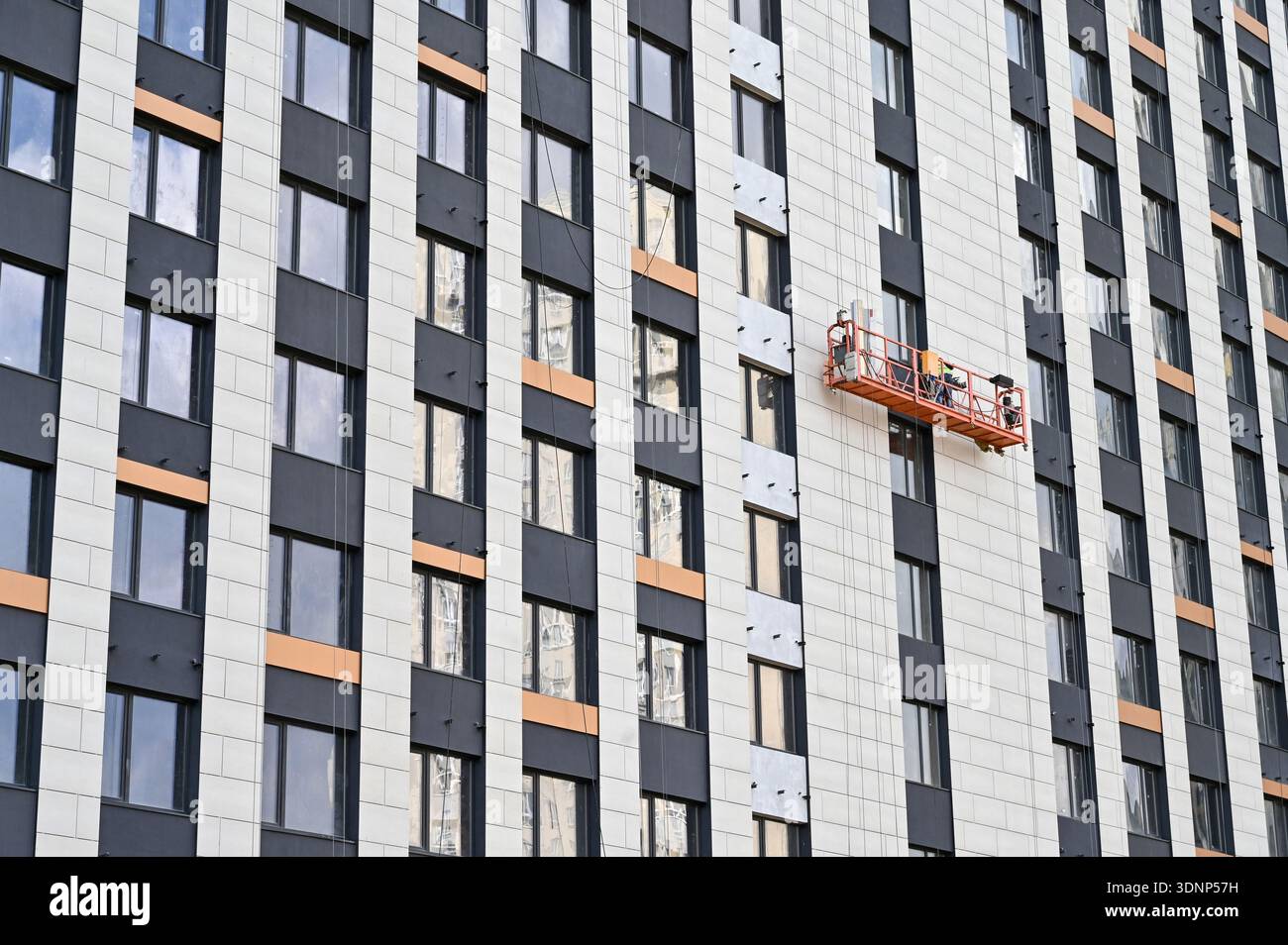 Teeming Platform A construction worker, on a suspended platform, completes the exterior ...