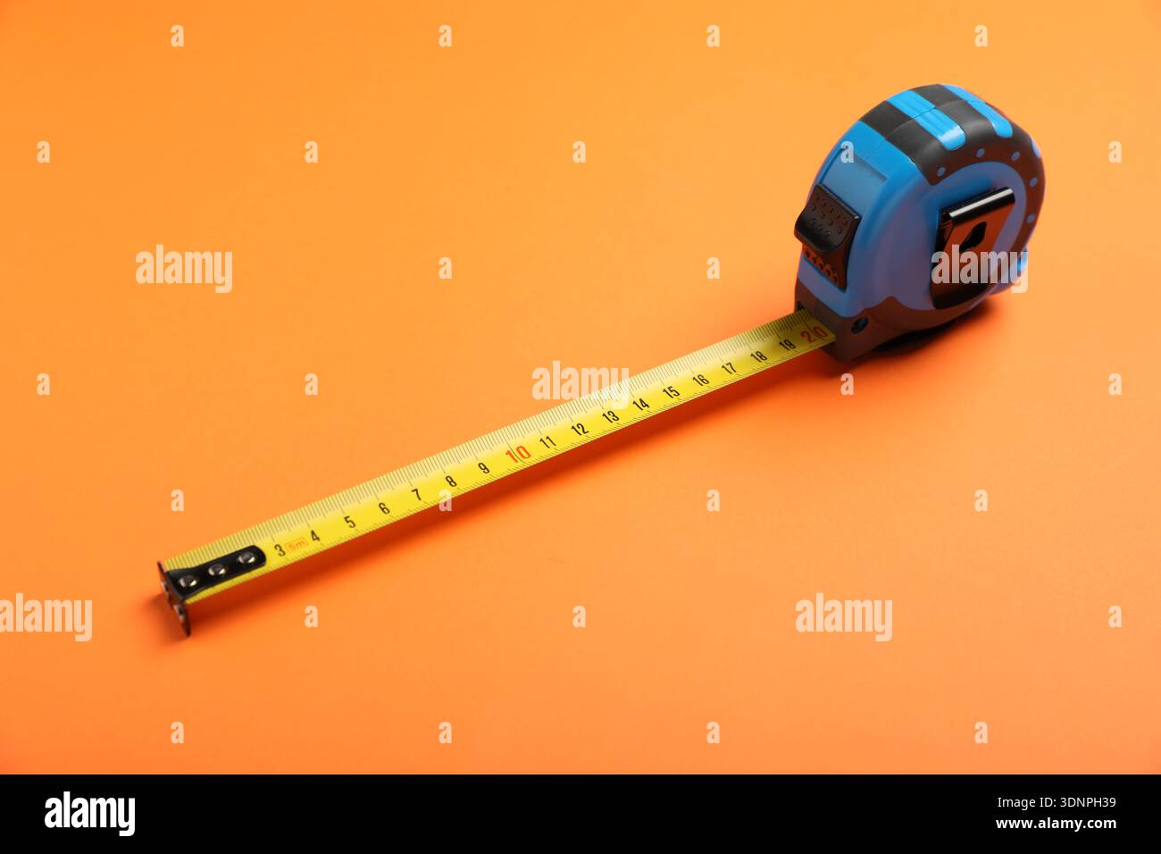 Blue measuring tape on orange background, closeup Stock Photo