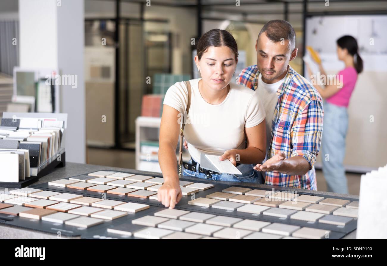 Interested couple browsing tile samples on display board in store Stock Photo