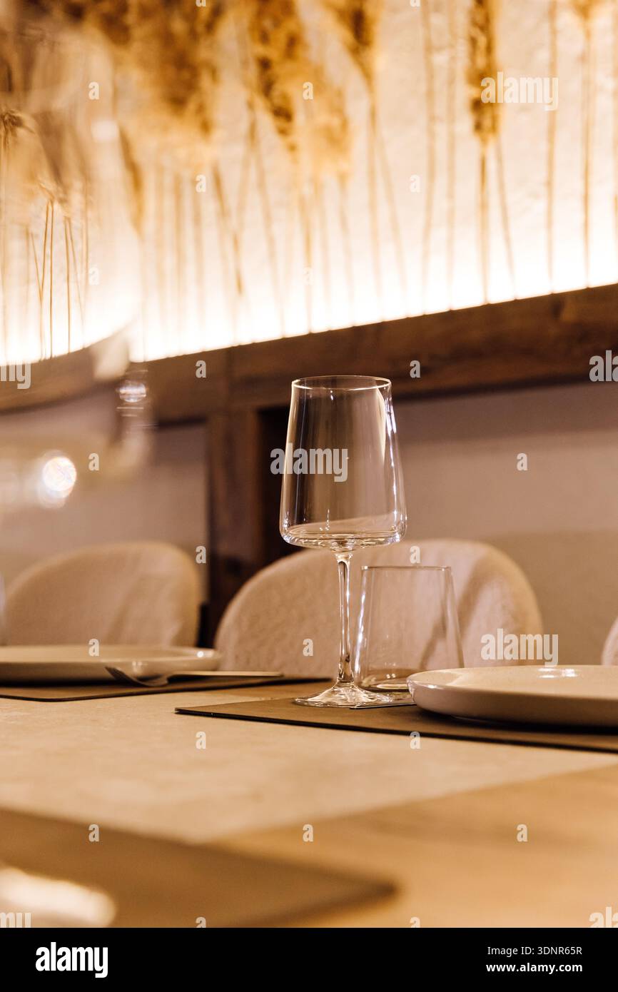 Wine glass on set restaurant table with warm candlelight and pampas decor Stock Photo