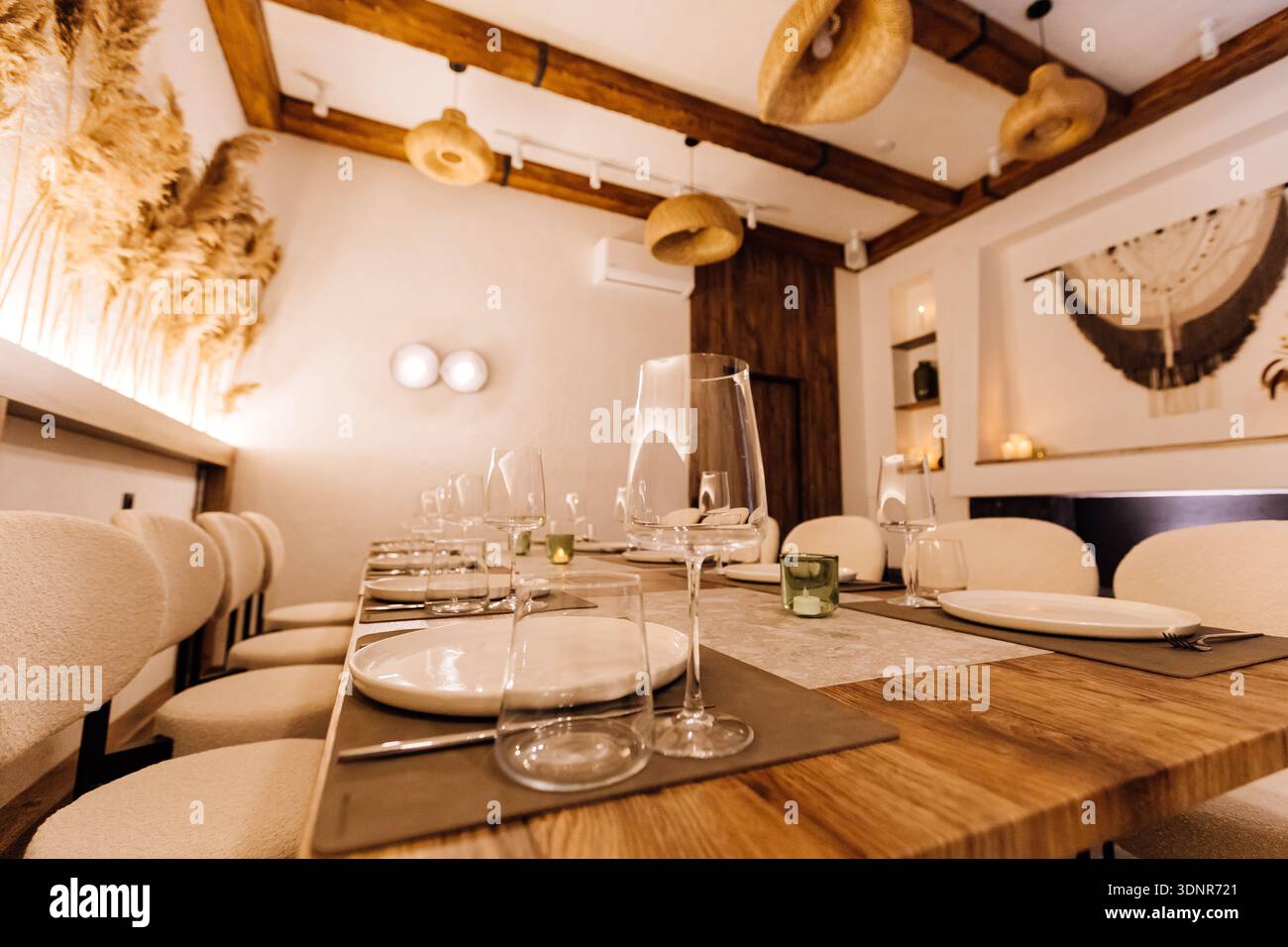 Boho private dining room with long table setting, pampas decor and warm light Stock Photo