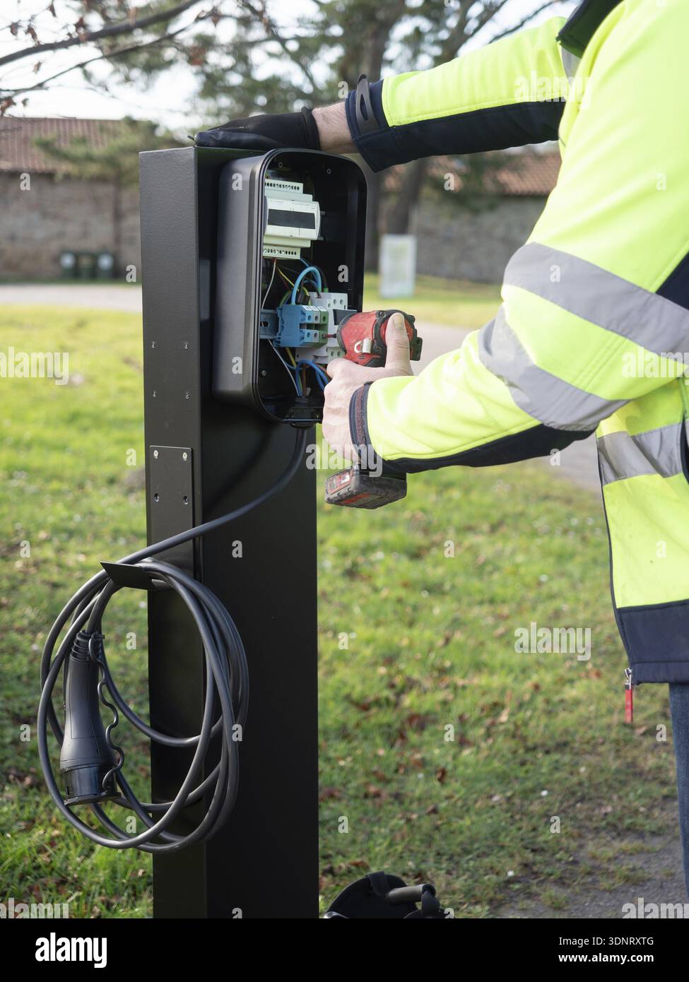 Worker installing an ev charging point, connecting wires and using a ...