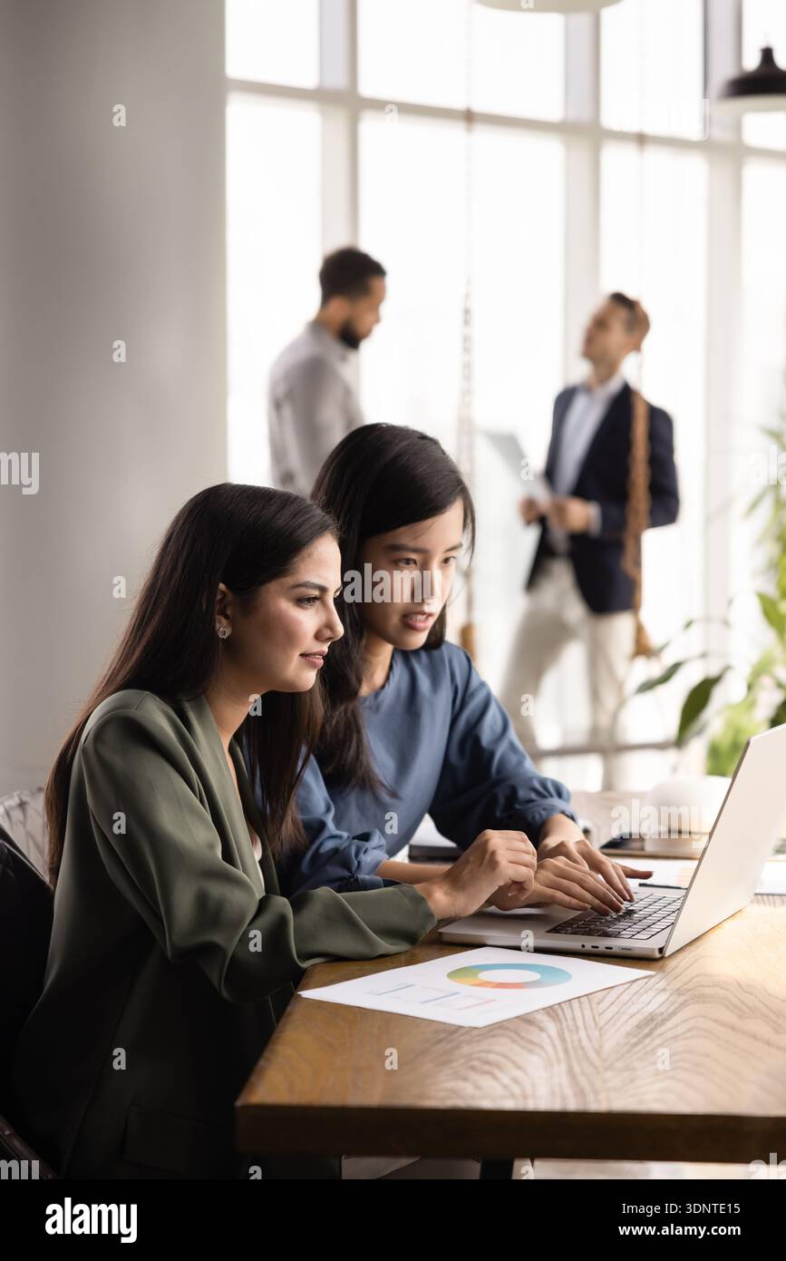 Two focused multiethnic analysts doing Internet marketing research Stock Photo