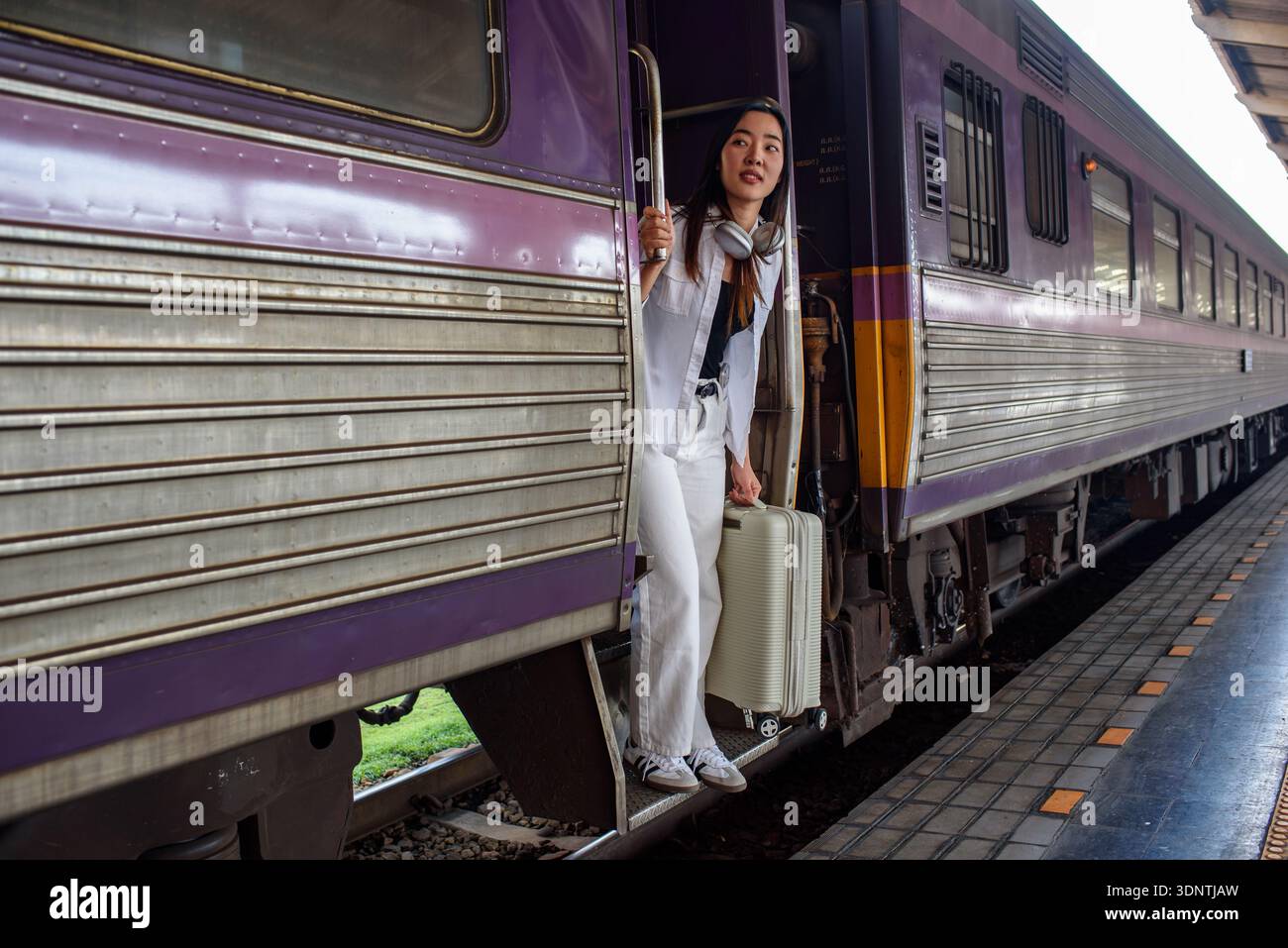 Young Asian woman stepping down from a passenger train at a railway ...