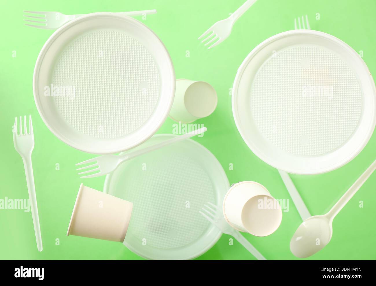 White plastic tableware levitating on green background Stock Photo