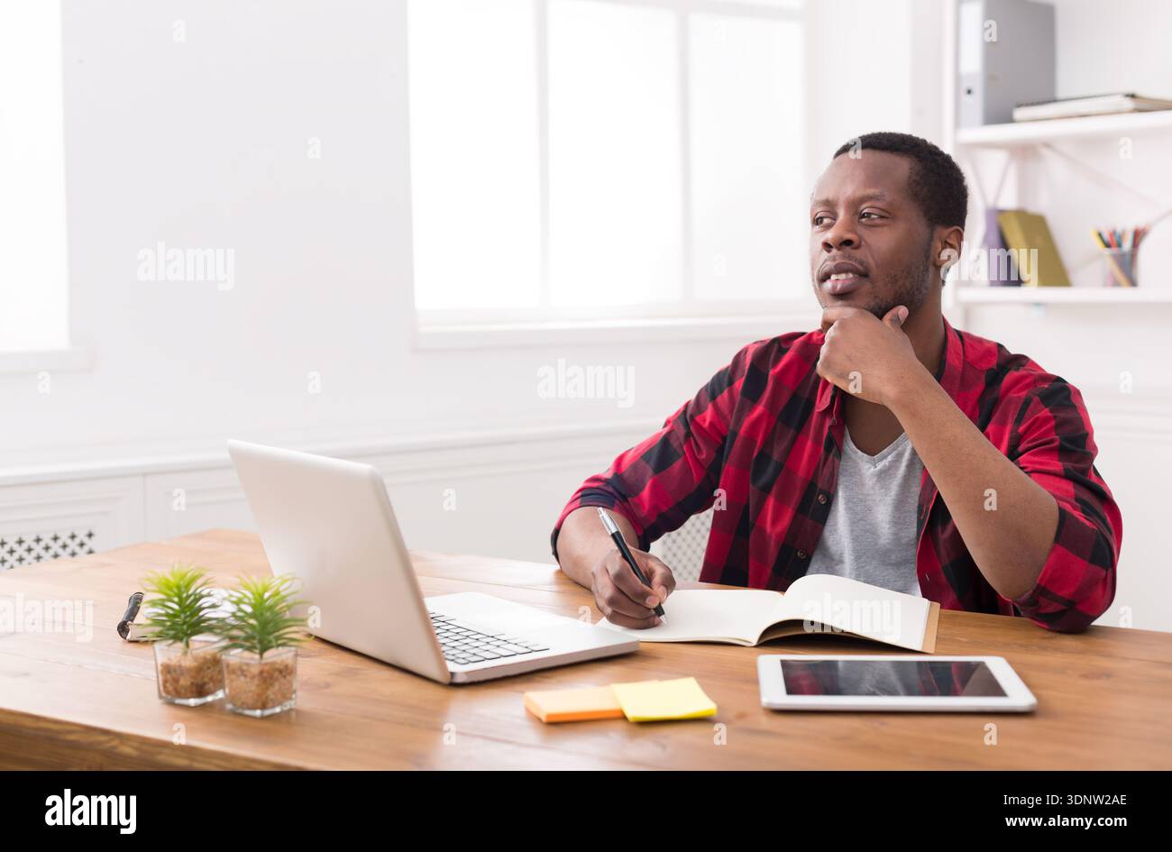 African american businessman using laptop and making notes Stock Photo