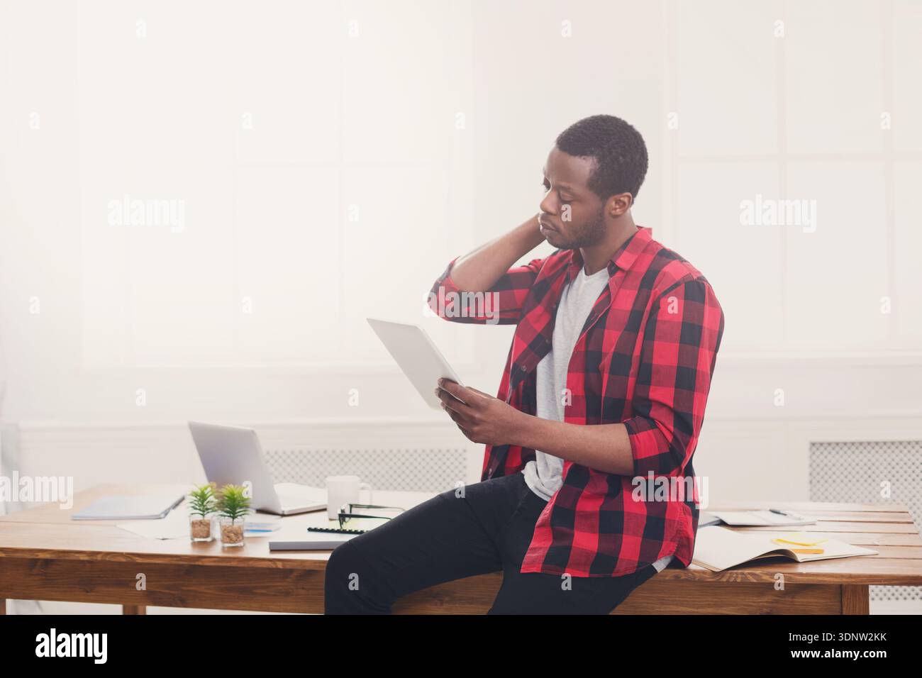 Stressed black businessman in modern office, work with tablet Stock Photo