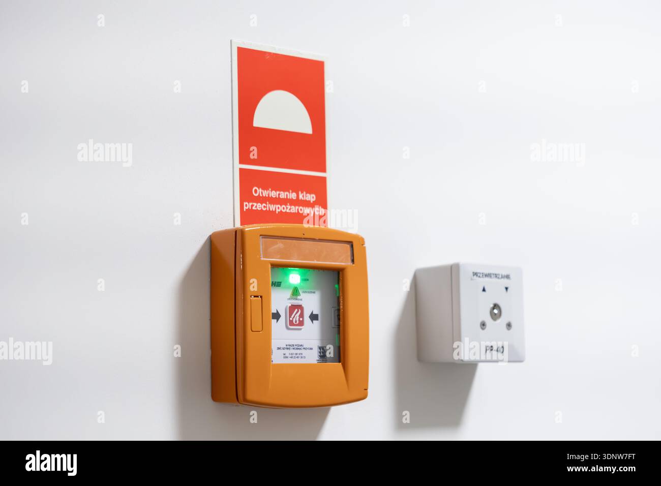 Krakow, Poland - November 30, 2025: Orange fire control button with green light, 'Opening fire dampers' sign, beside 'Ventilation' panel, essential fo Stock Photo