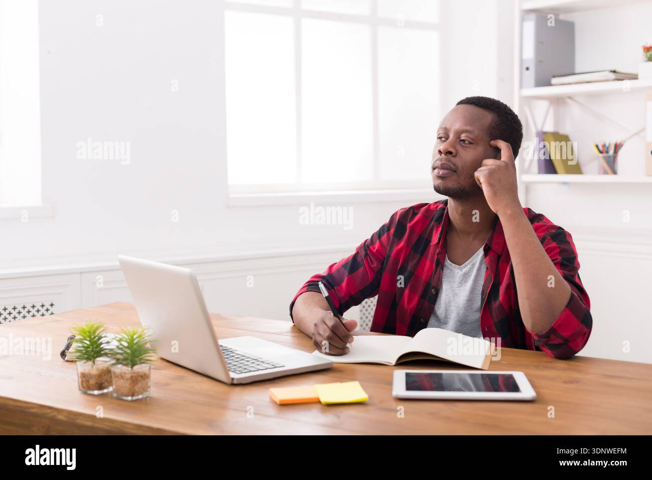 African american businessman using laptop and making notes Stock Photo
