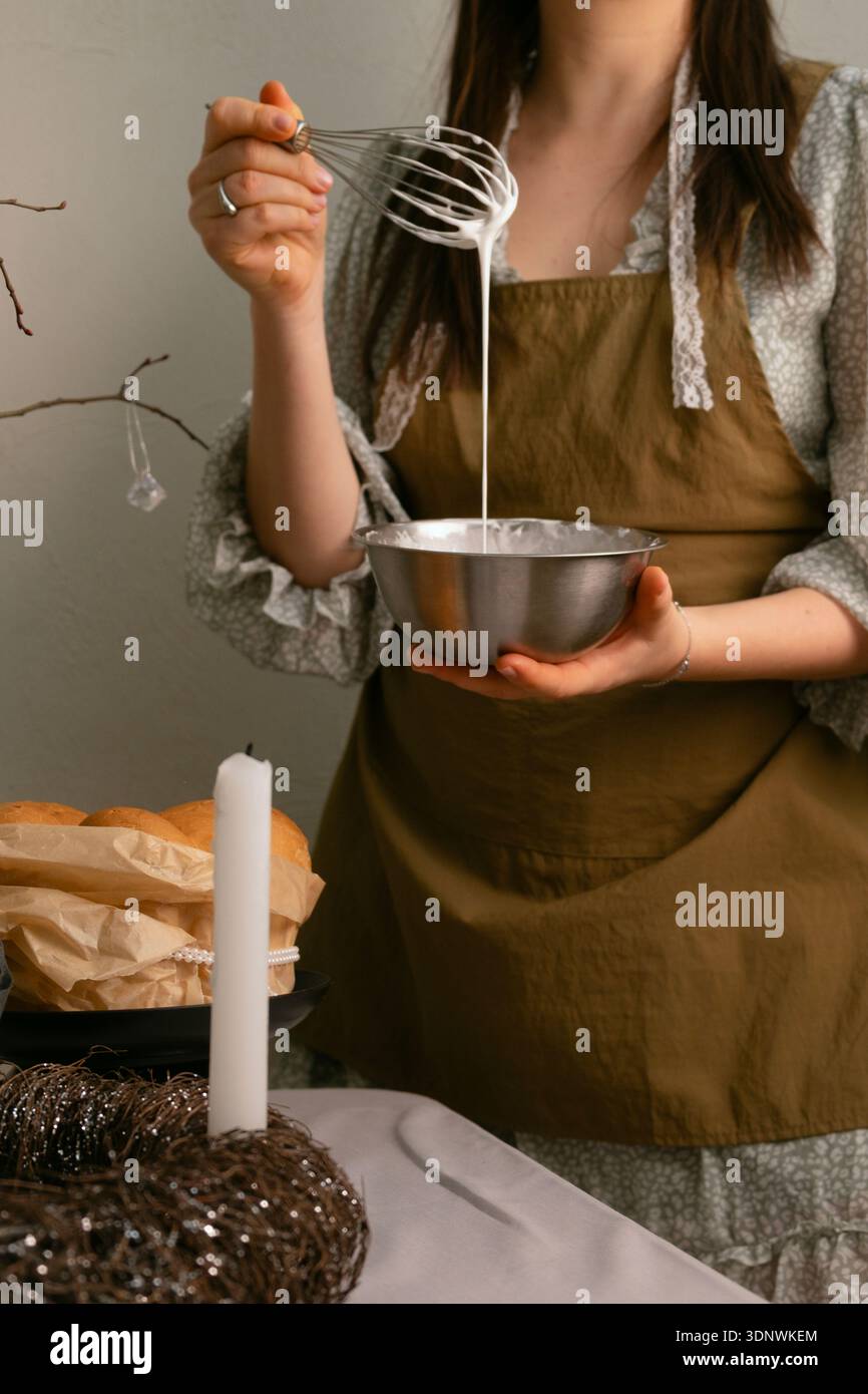 Traditional Easter celebration preparing glaze for Easter cake with eggs and candles Stock Photo