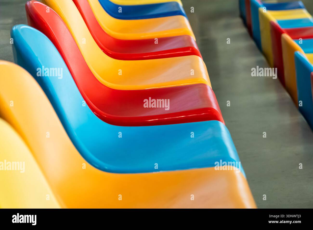 Colourful plastic stadium seats forming diagonal abstract pattern Stock Photo