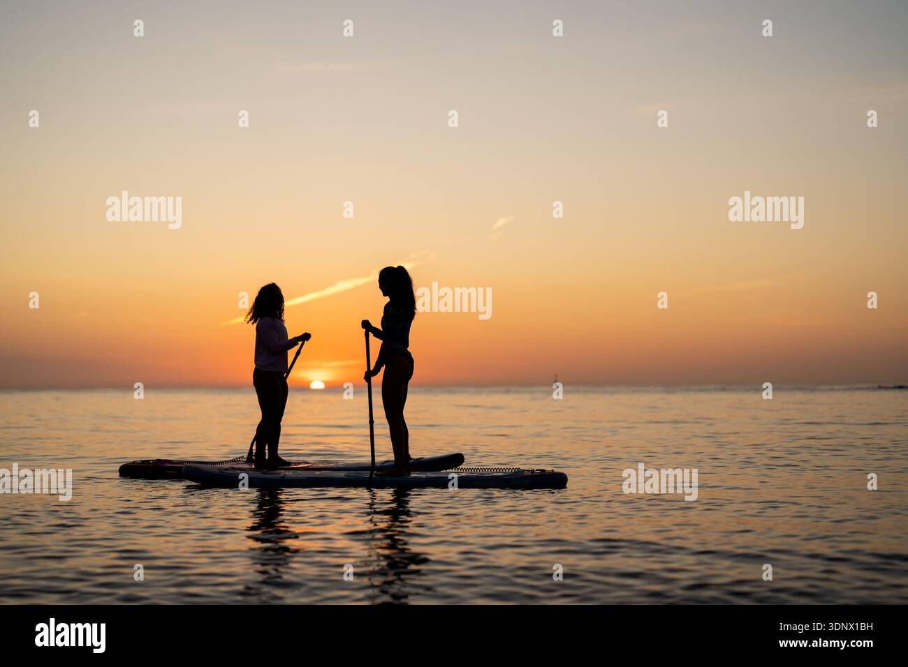 Couple of tourists young man and woman having fun paddle boarding at sea Stock Photo