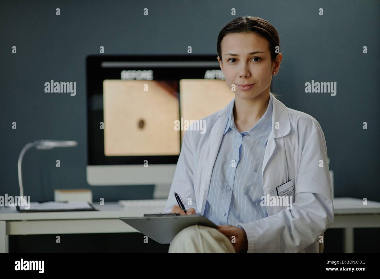 Smiling Young Caucasian Female Dermatologist Holding Clipboard in Office Stock Photo