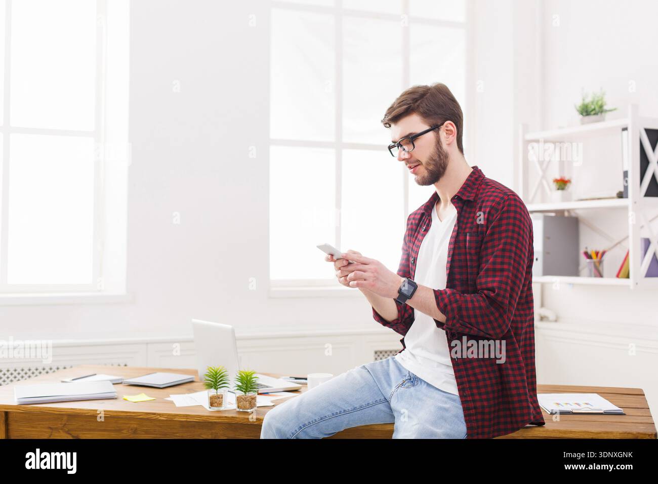 Relaxed young businessman using mobile in office Stock Photo