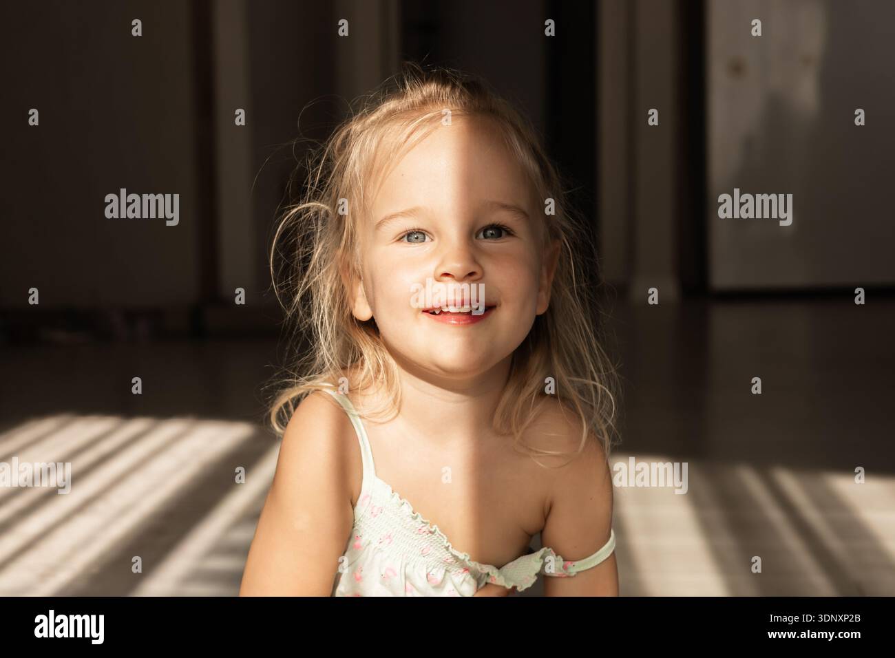 a-joyful-toddler-girl-with-blonde-hair-sits-indoors-smiling-warmly-as