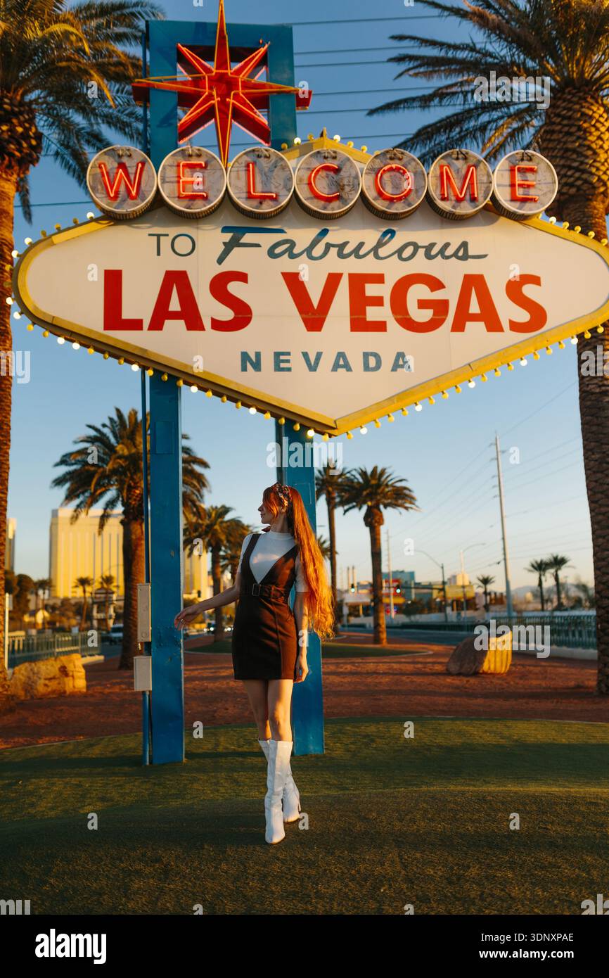 A tourist stands beneath the iconic Las Vegas welcome sign at sunset ...