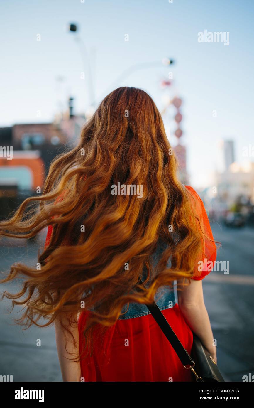 A woman with long red hair walks down a vibrant Las Vegas street. Neon ...