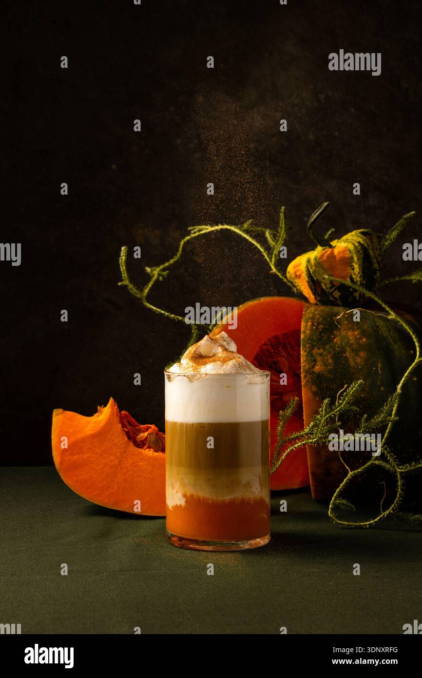 A glass of pumpkin spice latte topped with whipped cream stands against ...