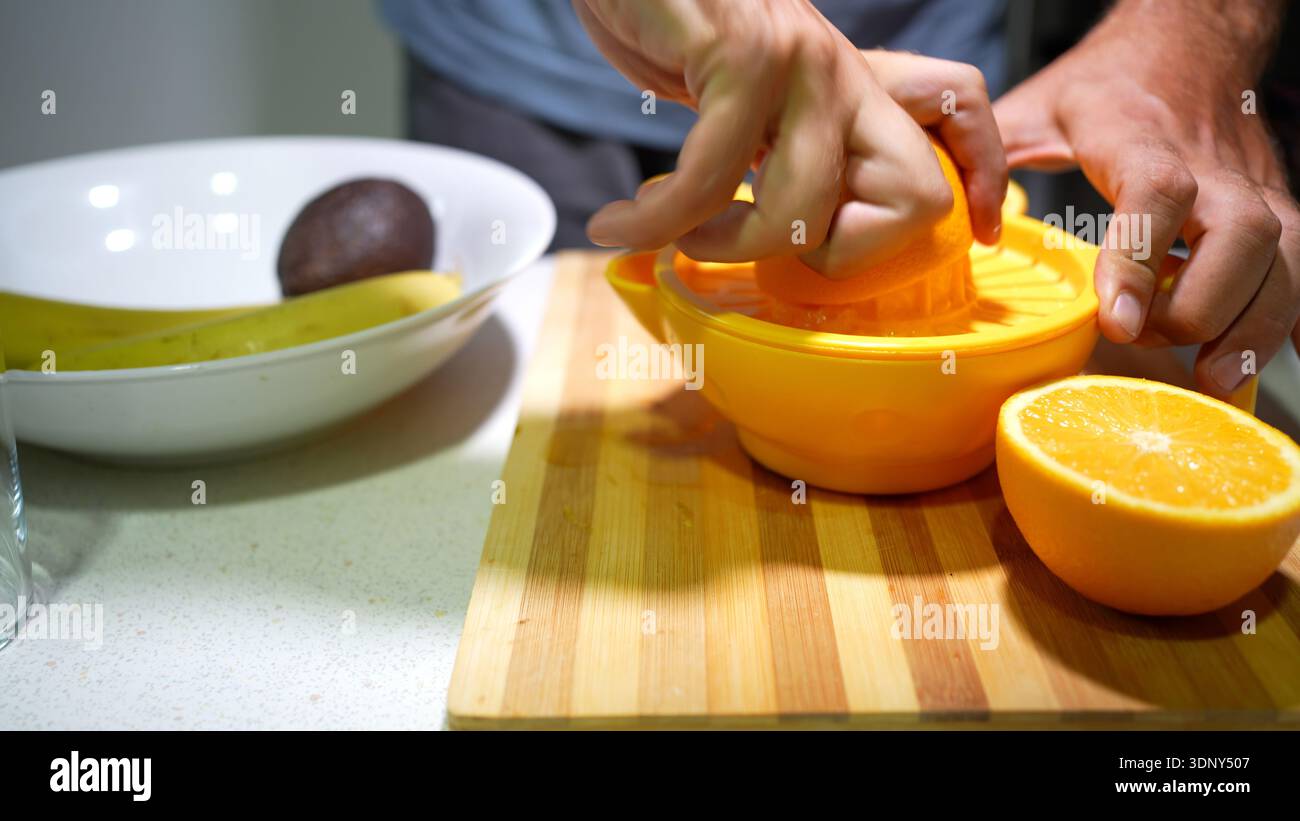 Juicing oranges on kitchen table. Casual kitchen setup for extracting fresh orange juice Stock Photo
