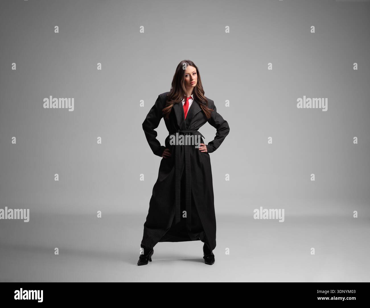 Female model wearing a long black coat with red tie Stock Photo - Alamy