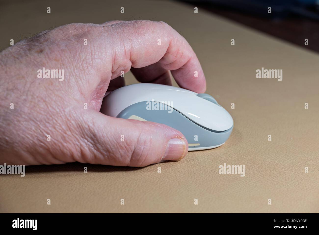 A person's hand is using a bluetooth computer mouse to navigate a digital interface attached to a computer Stock Photo