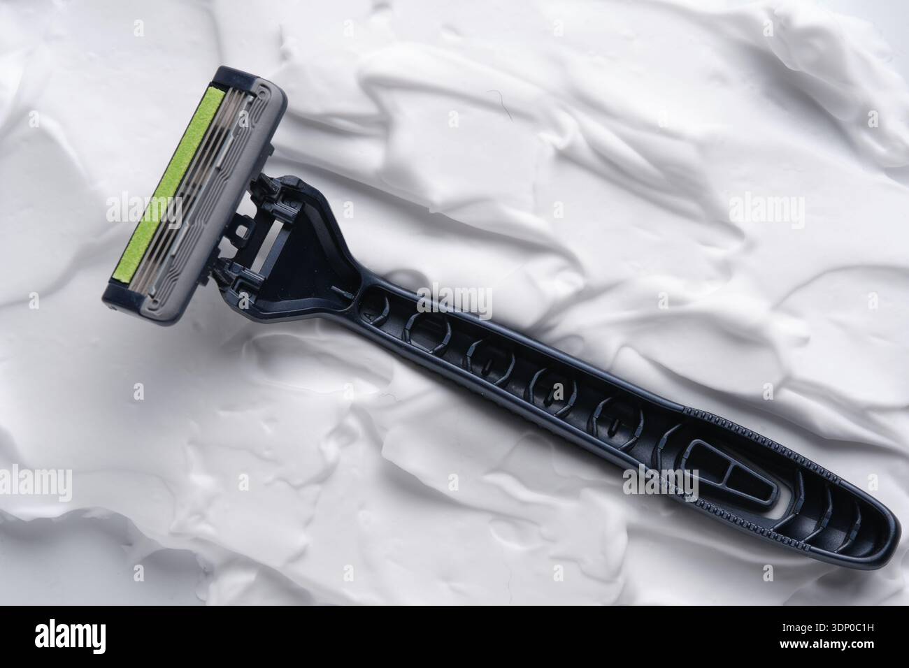 Black disposable razor on white shaving foam background Stock Photo