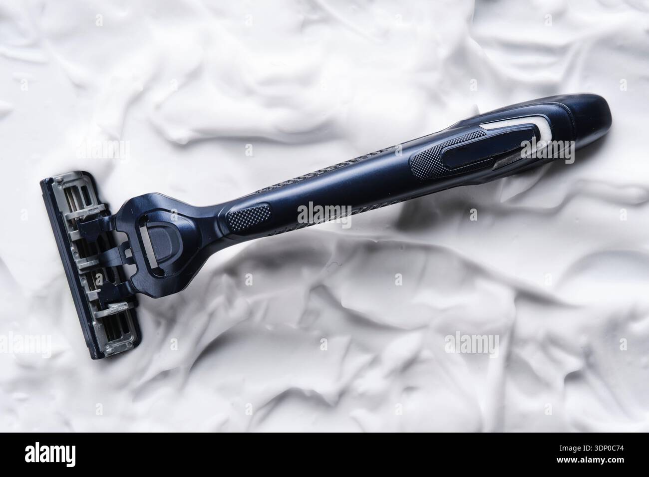 Modern razor with multi blade head lying horizontally in thick layer of ...