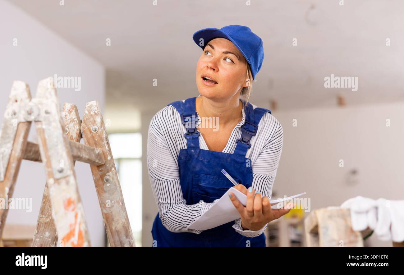 Female contractor taking notes while planning works at building site Stock Photo