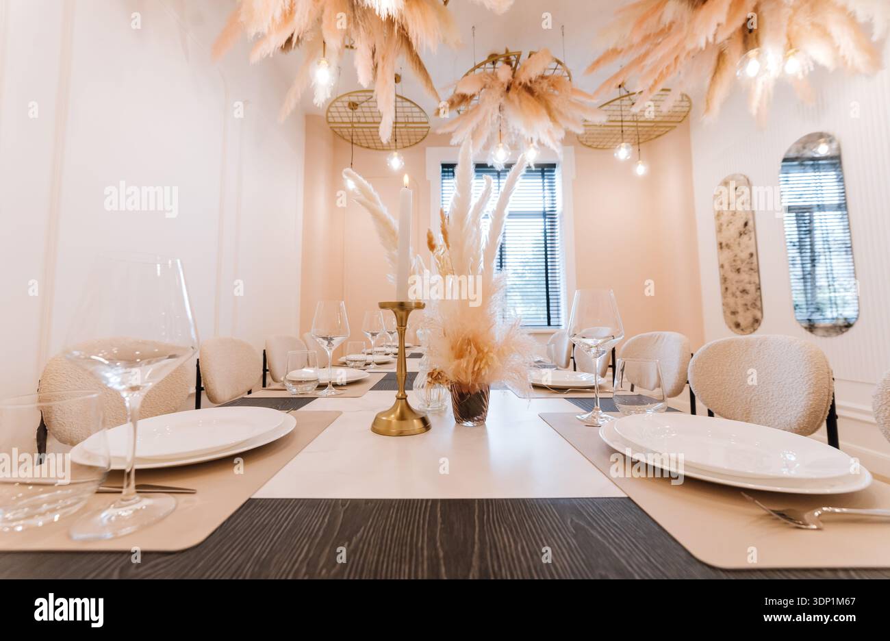 Neutral private dining table with pampas centerpiece, candlelight and modern decor Stock Photo