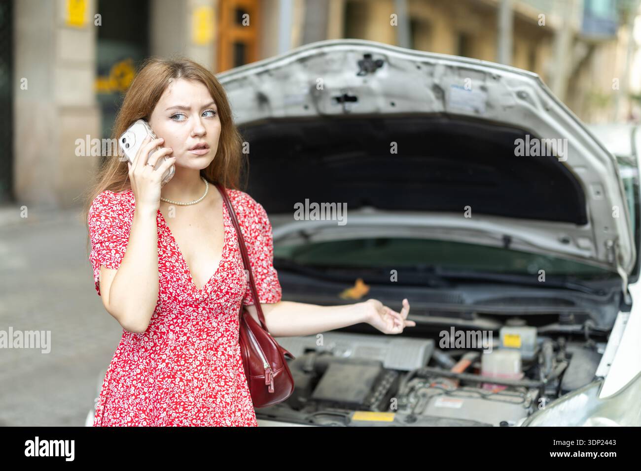 woman stands near a broken car with a phone in her hands Stock Photo