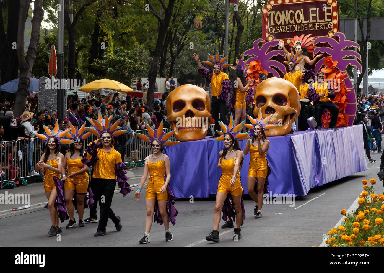 People walk and ride on a float with giant skulls during a Day of the Dead parade on Paseo de la Reforma Avenue in Mexico City, Mexico Stock Photo