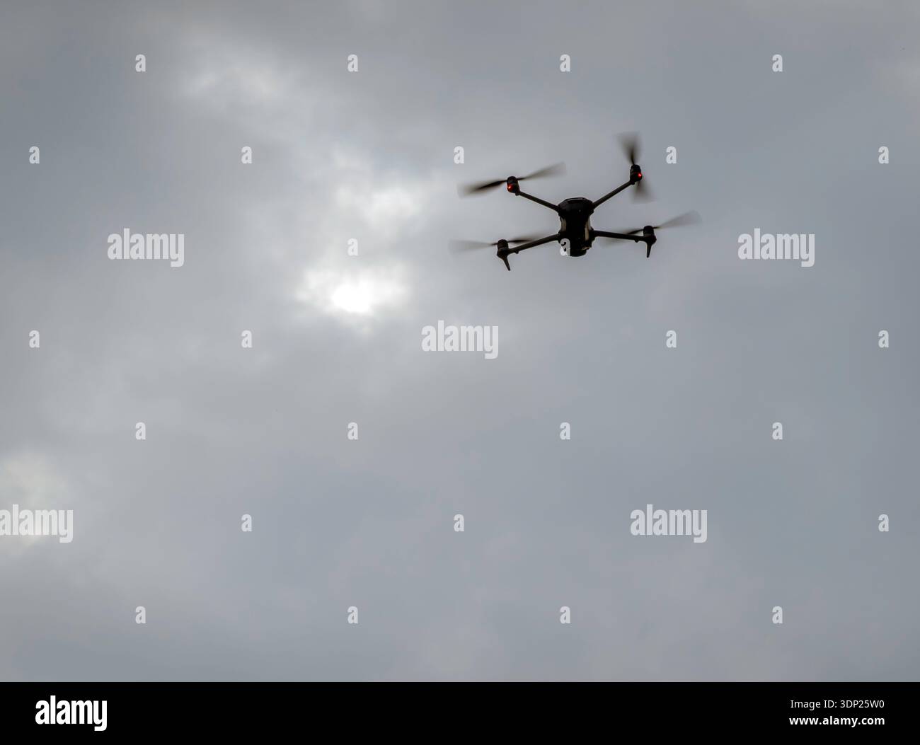 Quadcopter drone flying against a background of  grey clouds with copy space Stock Photo