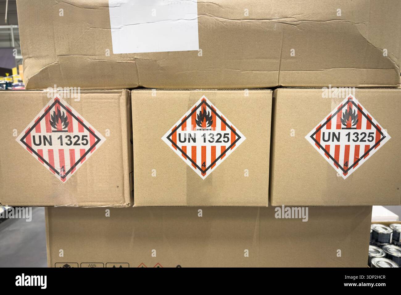 Cardboard packages stacked in a warehouse with UN 1325 hazard labels ...