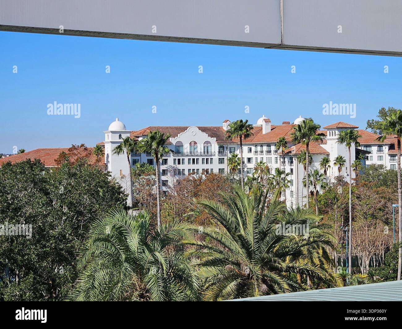 ​EDITORIAL USE ONLY- ORLANDO FLORIDA- Exterior view of the Hard Rock Hotel at Universal Orlando Resort, Florida, seen from a water taxi on the Universal waterway. The luxury hotel features Spanish Mission-style architecture with white facades and terracotta tile roofs under a clear blue sky. - Smartphone Captured Stock Image