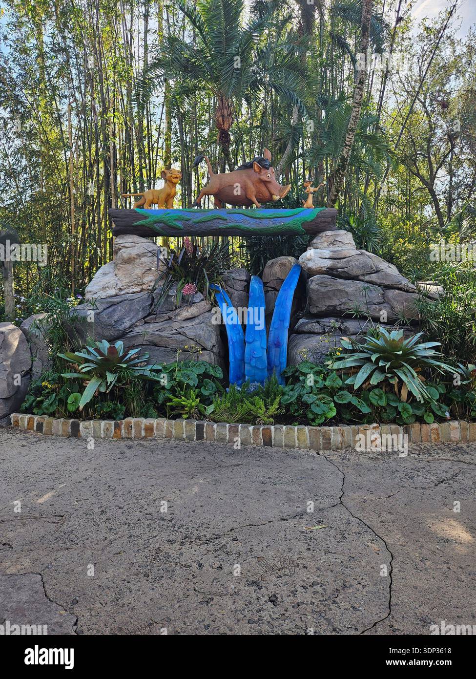 EDITORIAL USE ONLY- ORLANDO FLORIDA:  A colorful outdoor character display featuring Simba, Pumbaa, and Timon from Disney's "The Lion King" walking across a log. The statues are set atop a rock formation with lush tropical plants and tall bamboo in the background at a theme park. - Smartphone Captured Stock Image
