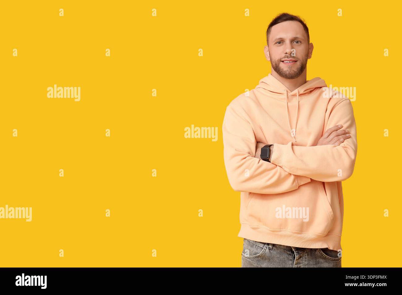 Stylish young man in hoodie on yellow background Stock Photo