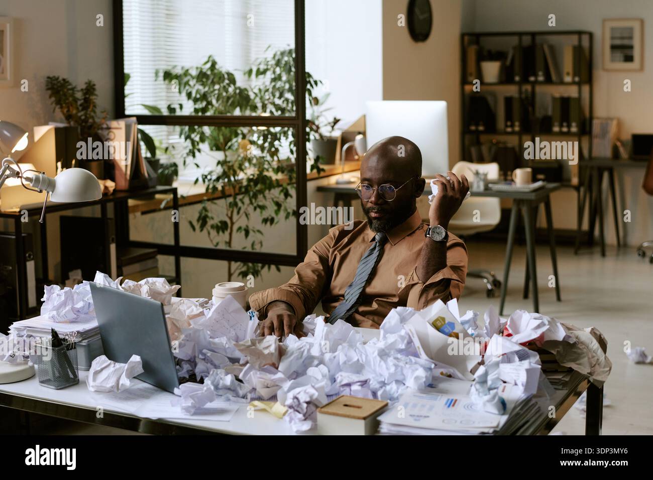 Black Man Sitting at Desk Handling Stressful Office Workload Stock Photo