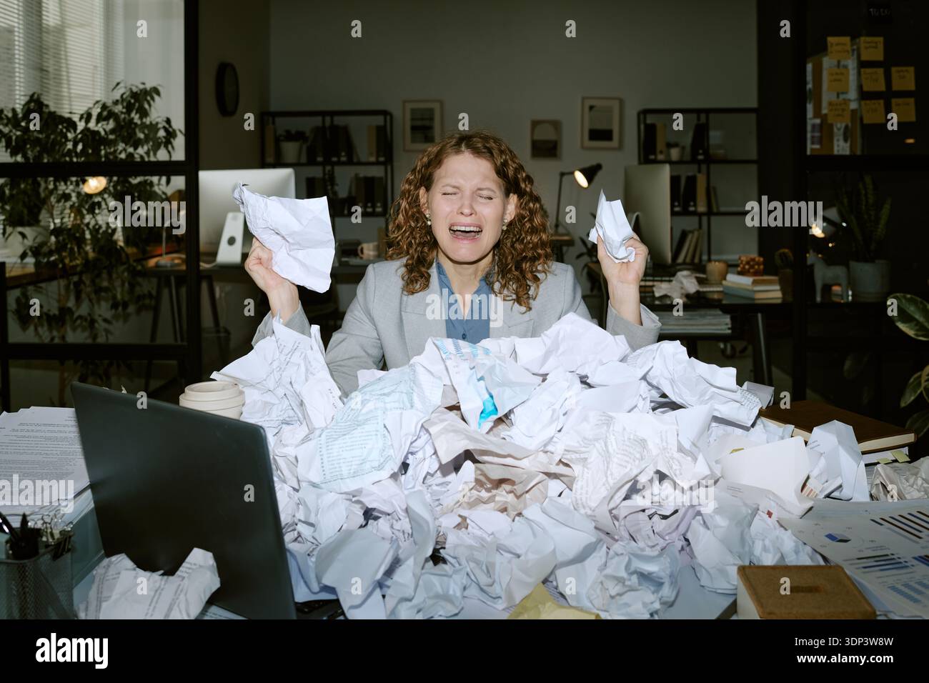 Stressed Young Woman Sitting at Desk Handling Paperwork Stock Photo