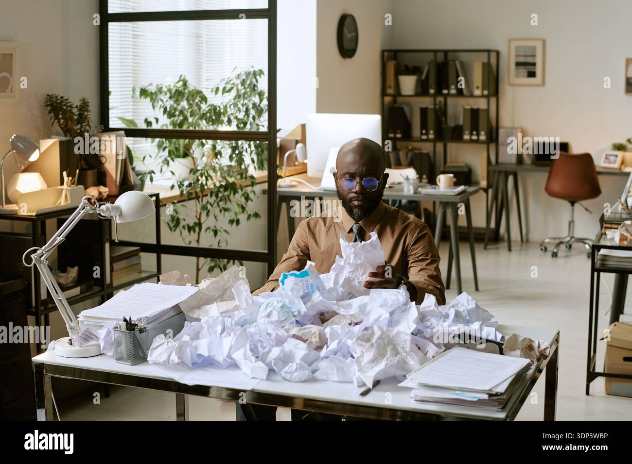 Black Man Reviewing Documents at Desk in Modern Business Office Stock Photo