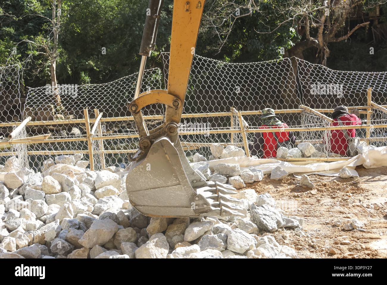 Yellow excavator bucket at construction site, moving rock with heavy ...