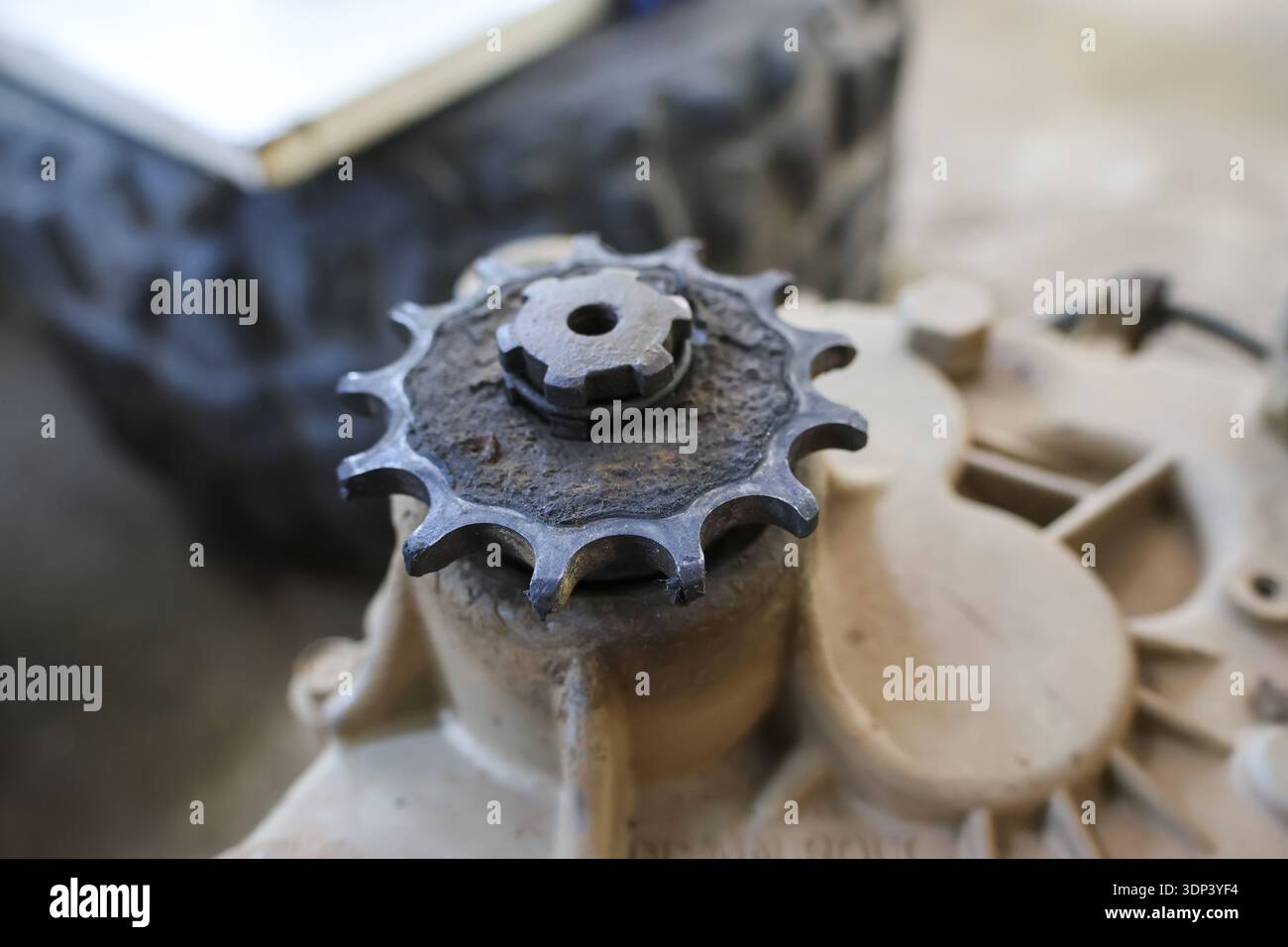 Dirty metal sprocket gear cog from an engine part, covered in grime. Close up detail of mechanical component needing repair or maintenance in workshop Stock Photo