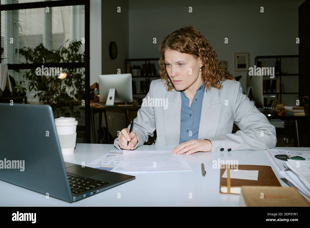 Woman Analyzing Financial Documents While Working in Office Stock Photo