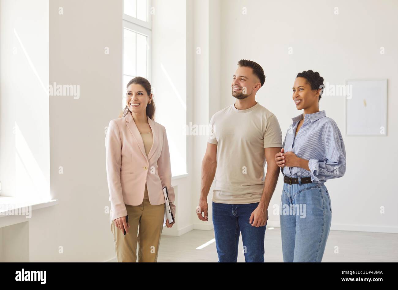 Real estate agent, realtor presenting young couple modern indoor space, professional consultation Stock Photo