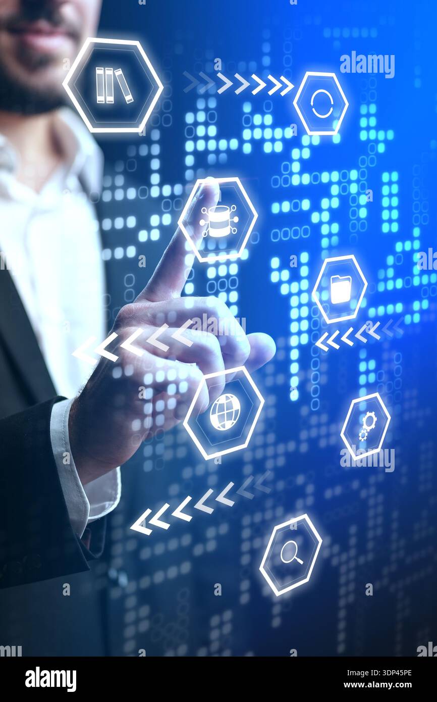 Businessman interacts with digital interface and data icons in an office setting Stock Photo